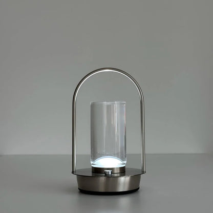 The Minimalist Arch Metal Portable Table Lamp turned on with a bright white light. - RoomDen