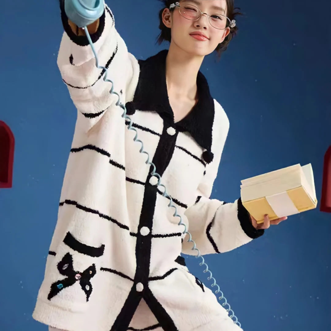 Playful shot of a model in the striped fleece pajama set winking while holding a book and telephone - RoomDen.