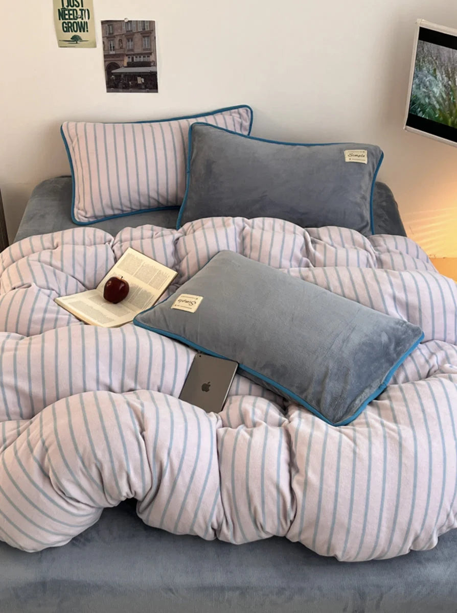 The Slate Grey Striped Flannel Fleece Bedding Set styled with grey pillows and an open book. - RoomDen
