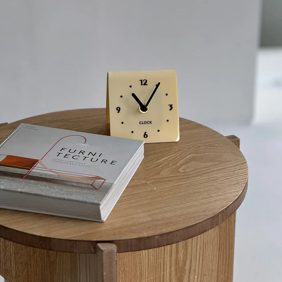 Lifestyle scene of the cream beige minimalist clock on a wooden table. - RoomDen