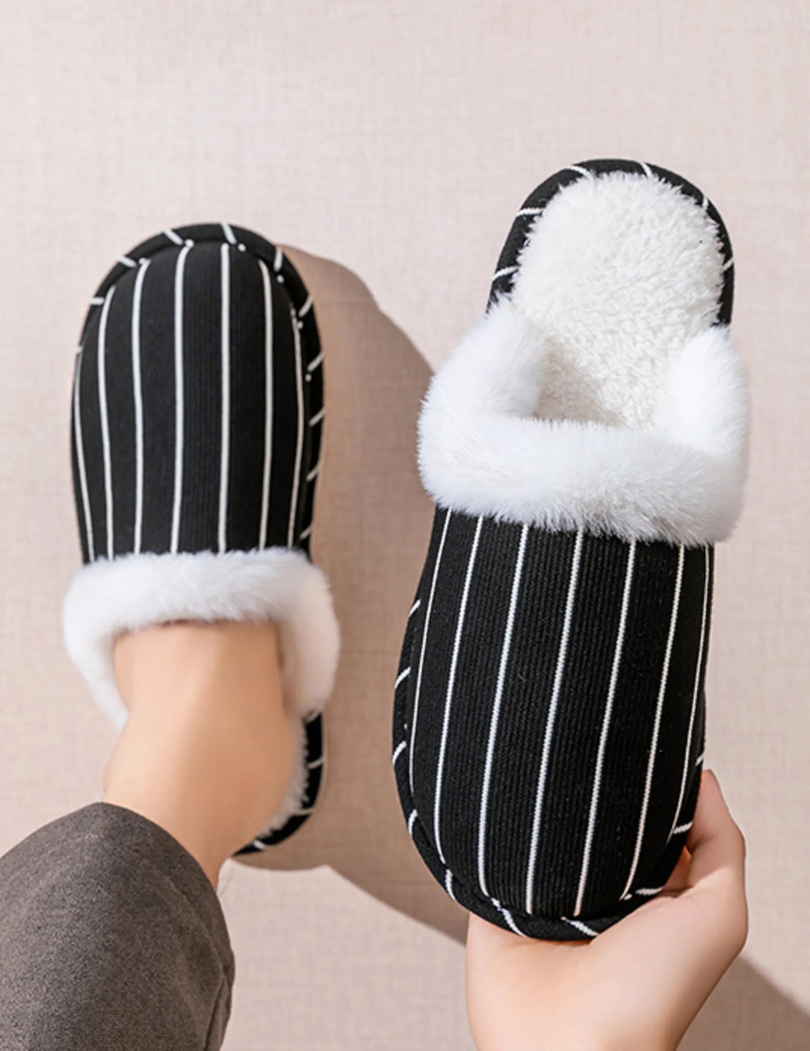 Hand holding a Black and White striped slipper showing sole flexibility - RoomDen