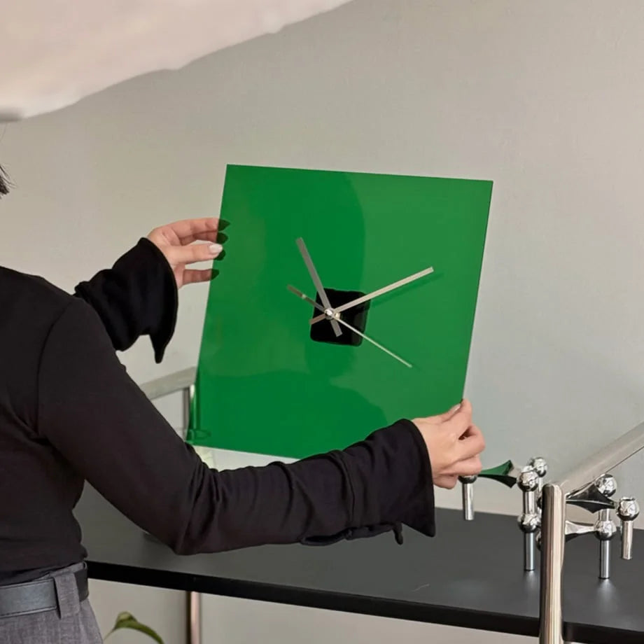 Person adjusting the Emerald Green square acrylic clock on a shelf. - RoomDen