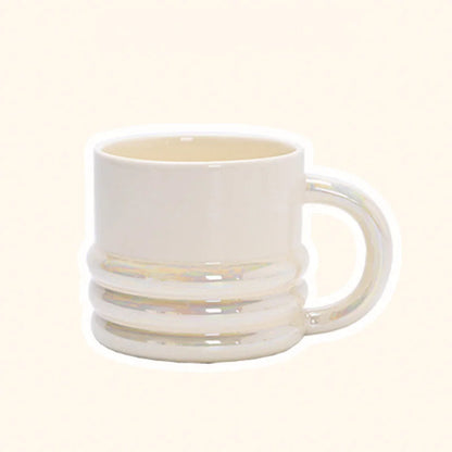 Close-up of a chunky ribbed ceramic mug in an iridescent white finish on a plain background - RoomDen.