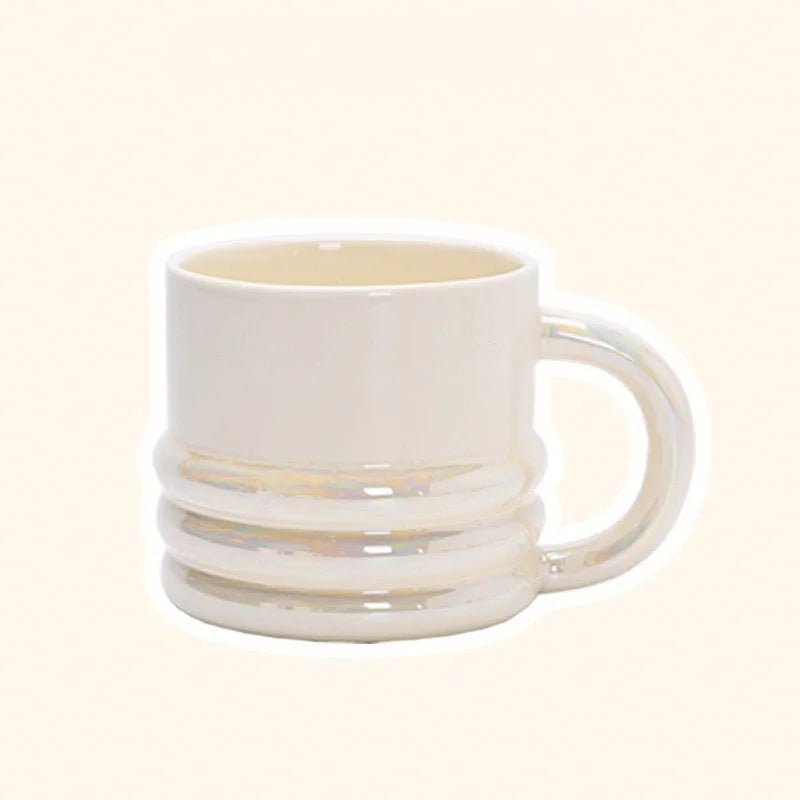 Close-up of a chunky ribbed ceramic mug in an iridescent white finish on a plain background - RoomDen.