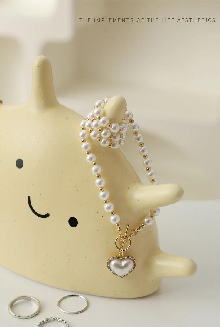 Creamy Beige Smiling Sun Ceramic Ring Holder with a pearl heart necklace draped over it - RoomDen