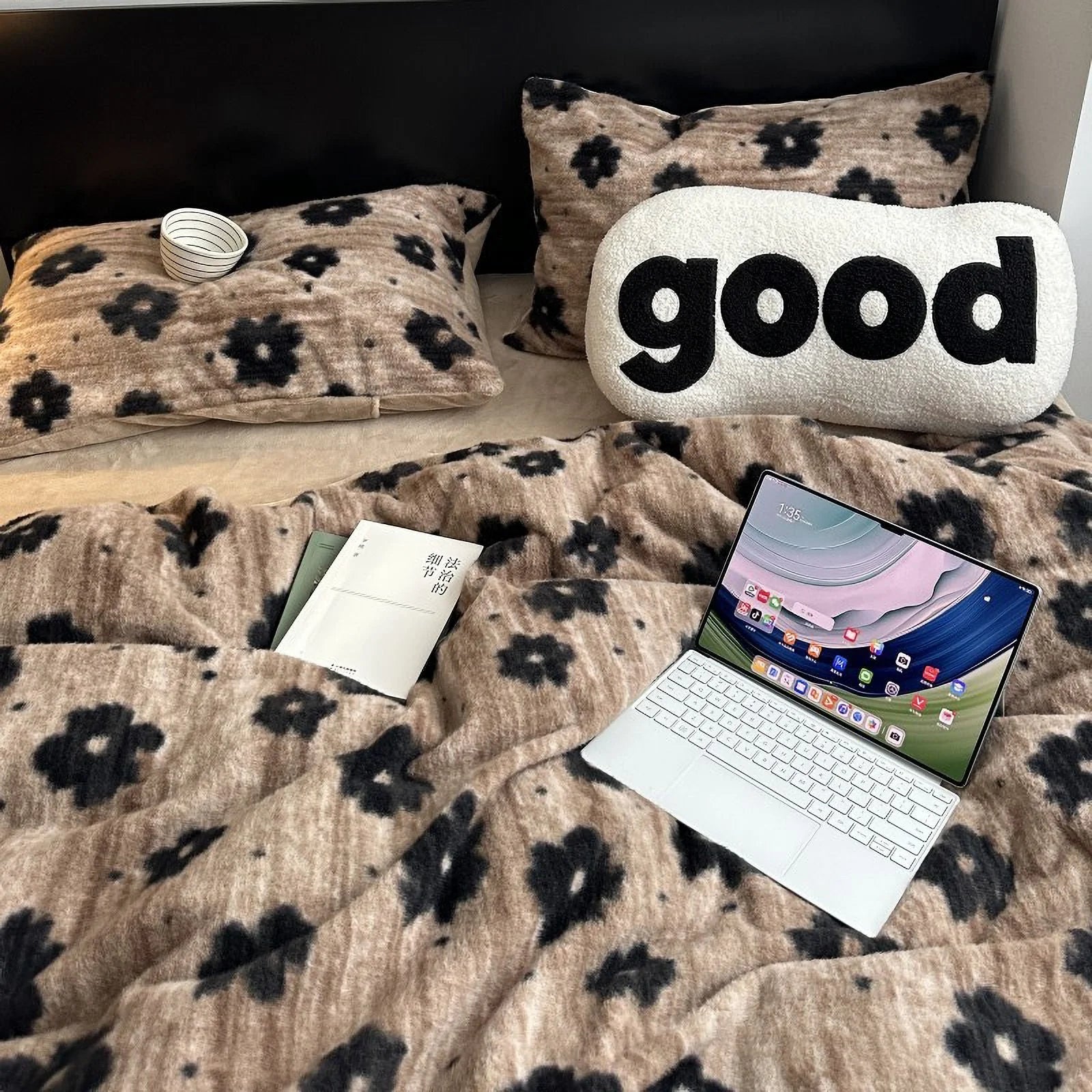 An overhead view of the plush retro floral flannel fleece bedding, showcasing the brown and black flower pattern with a laptop and book on the bed. - RoomDen