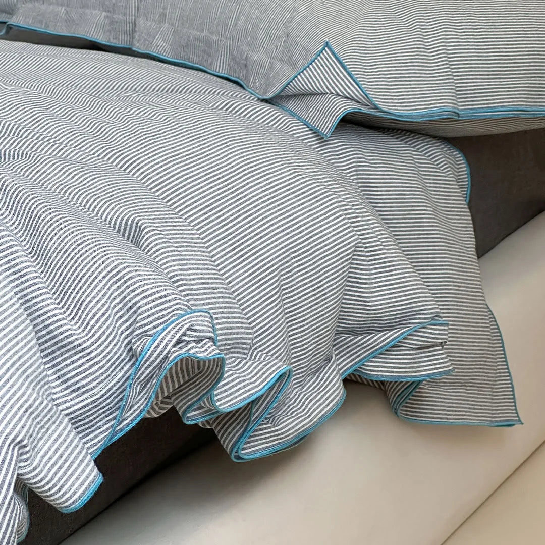 Detailed shot of the ruffled blue trim on the Dark Grey & Blue pinstripe duvet cover.