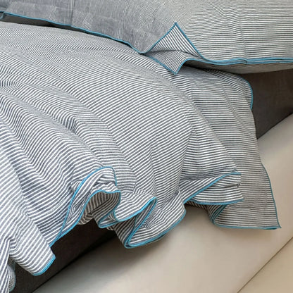 Detailed shot of the ruffled blue trim on the Dark Grey & Blue pinstripe duvet cover.