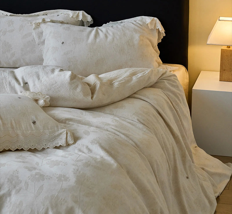 Lifestyle shot of the antique white linen bedding set in a cozy bedroom with a bedside lamp on — RoomDen