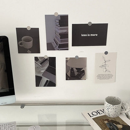 Black and white wall collage kit pinned to a white wall above a clean, modern desk with a computer and magazines. - RoomDen