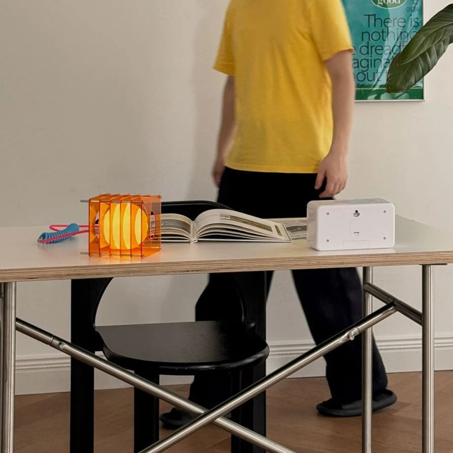 Full room view showing the Sunset Orange Caged Lamp on a desk with a person walking by - RoomDen