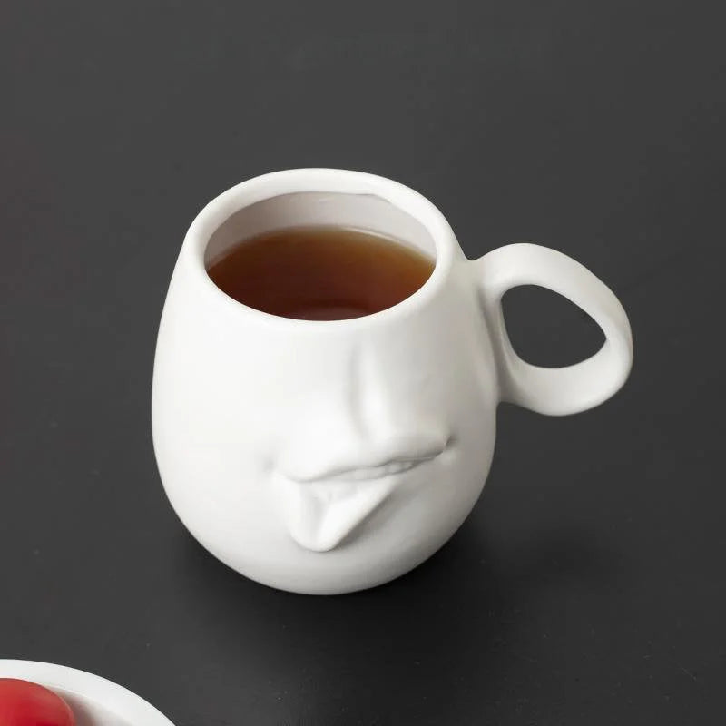 A matte white Sculptural Abstract Face Ceramic Mug filled with tea, seen from above.