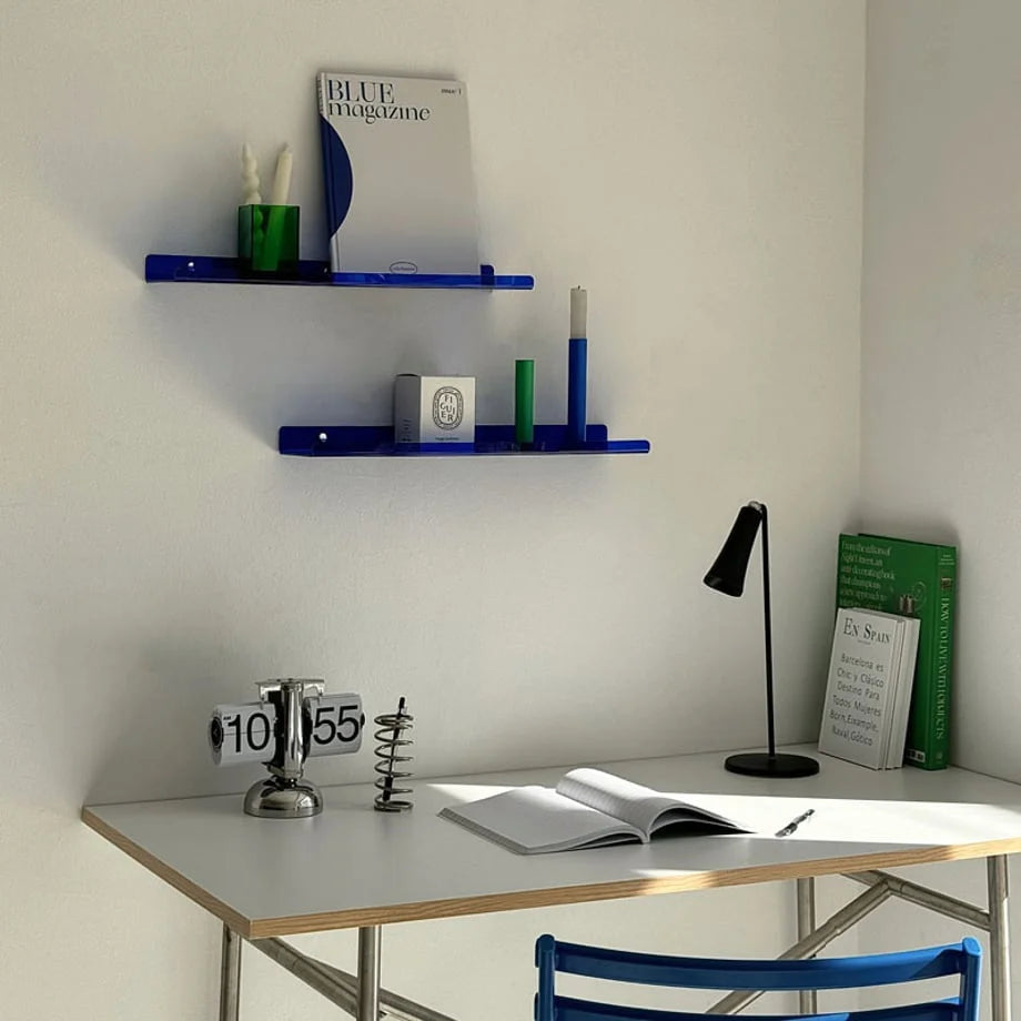 Lifestyle scene featuring two blue acrylic shelves above a modern white desk with a flip clock and lamp, showcasing an Indie decor style - RoomDen.