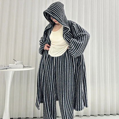 Model adjusting the top under her black and white striped hooded robe, showing the relaxed fit of the pajama set - RoomDen.