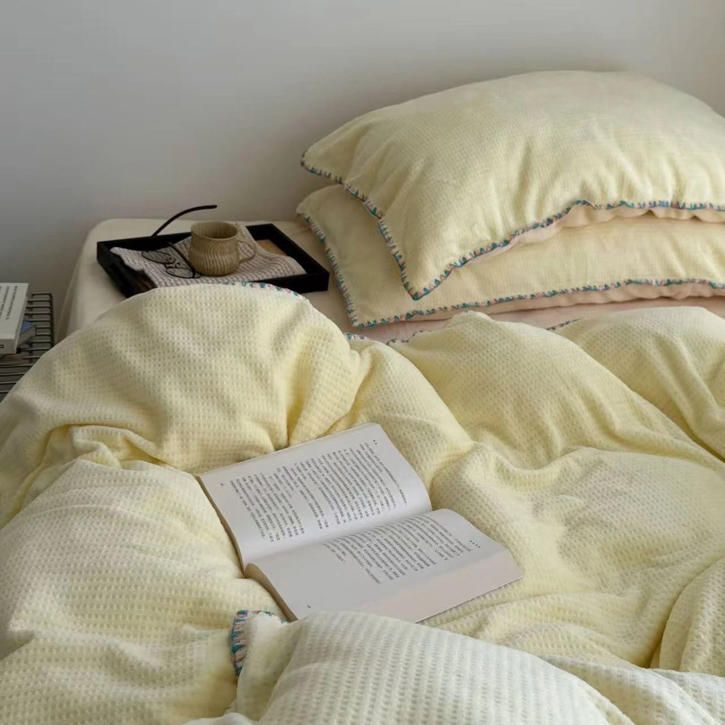 Close-up of an open book on the cozy Butter Yellow Waffle Fleece Duvet Cover.