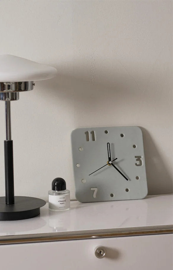 Light Grey ceramic cutout clock on a white nightstand next to a modern lamp - RoomDen.