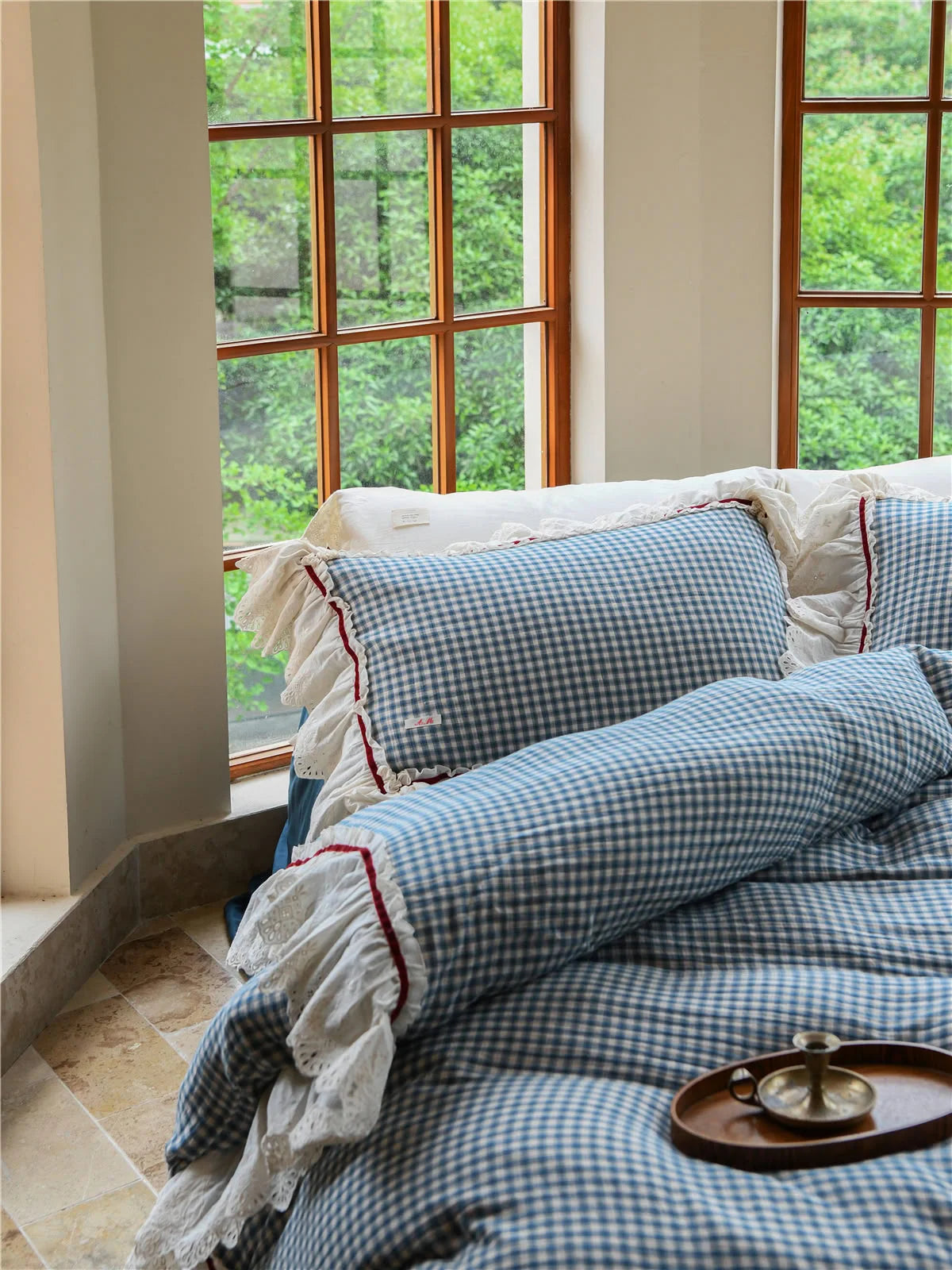 Detail shot of the Blue Gingham pillow sham with white lace ruffles and red piping accent.