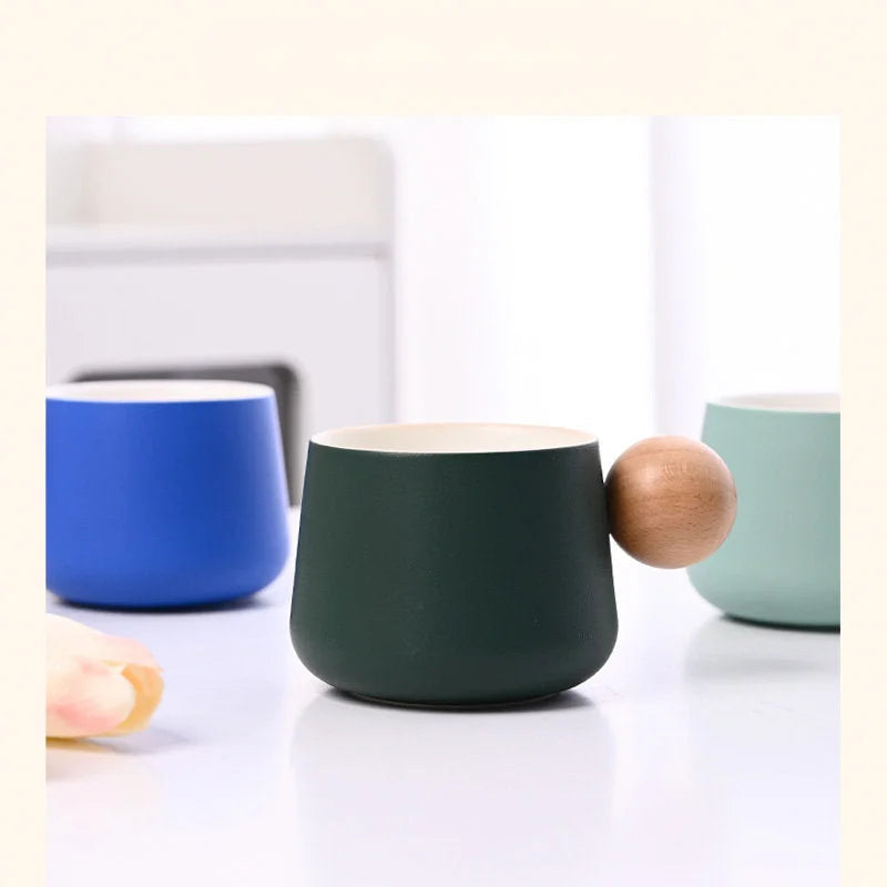 Close-up detail of the Dark Green and Blue Frosted Ceramic Mugs with their distinctive wooden sphere handles. - RoomDen