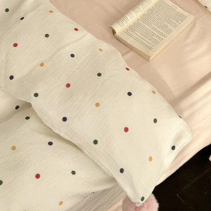 An overhead view of the soft white polka dot duvet cover with a book resting on the bed, highlighting the fabric's texture. - RoomDen