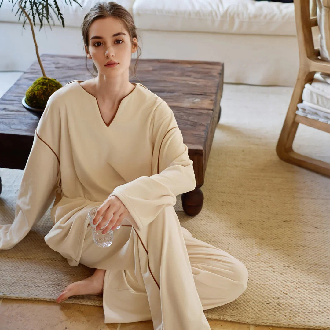 Model sitting on a jute rug in the creamy beige plush loungewear set, holding a glass of water. - RoomDen