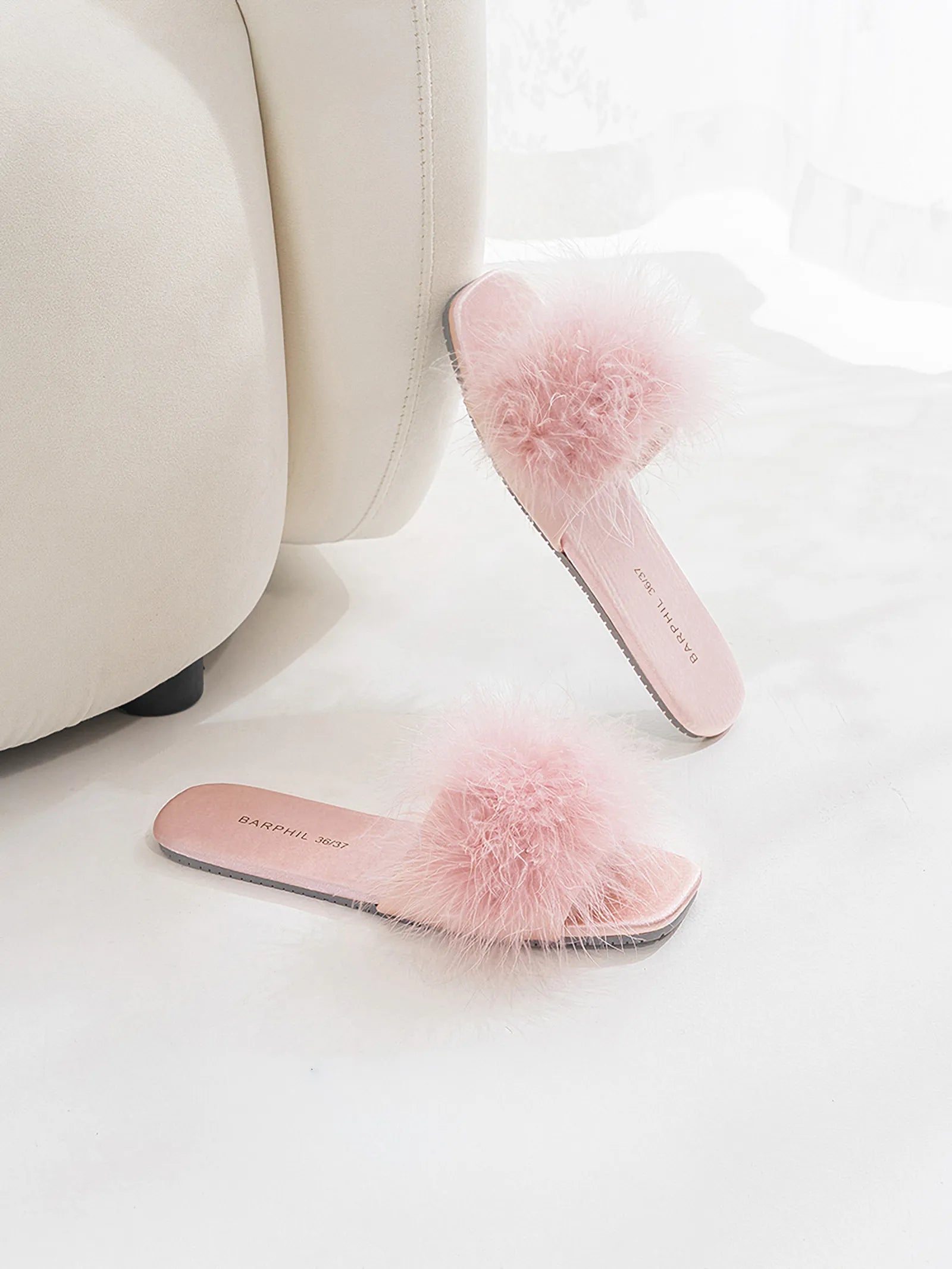 Lavender house slippers styled next to a cream sofa - RoomDen