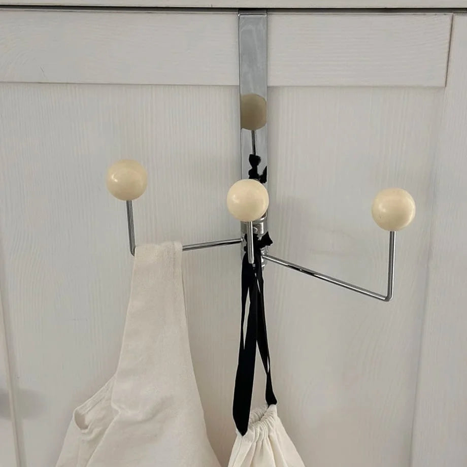 Front-facing view of the beige over-the-door hook holding a white bag and black ribbon - RoomDen