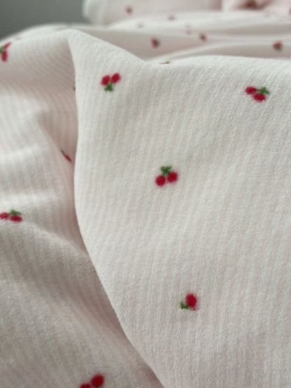 Macro shot showing the textured stripe fabric and embroidered-style cherry detail of the flannel fleece. - RoomDen