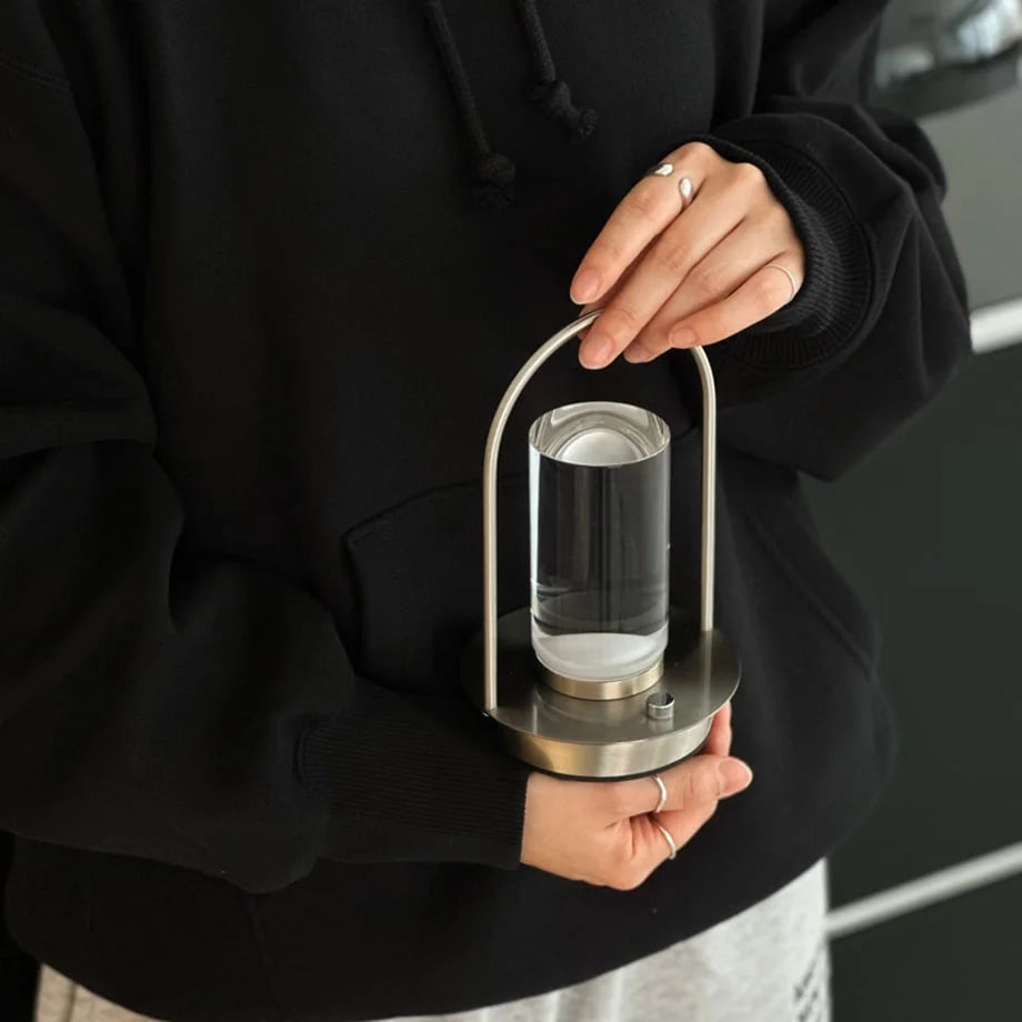 A person in a black hoodie holding the portable Minimalist Arch Metal Table Lamp. - RoomDen