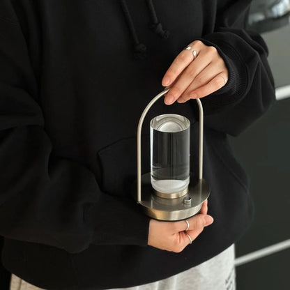 A person in a black hoodie holding the portable Minimalist Arch Metal Table Lamp. - RoomDen