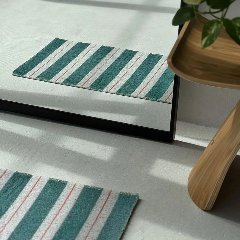 Reflection of a green striped PVC coil rug in a floor mirror showing its loop texture - RoomDen