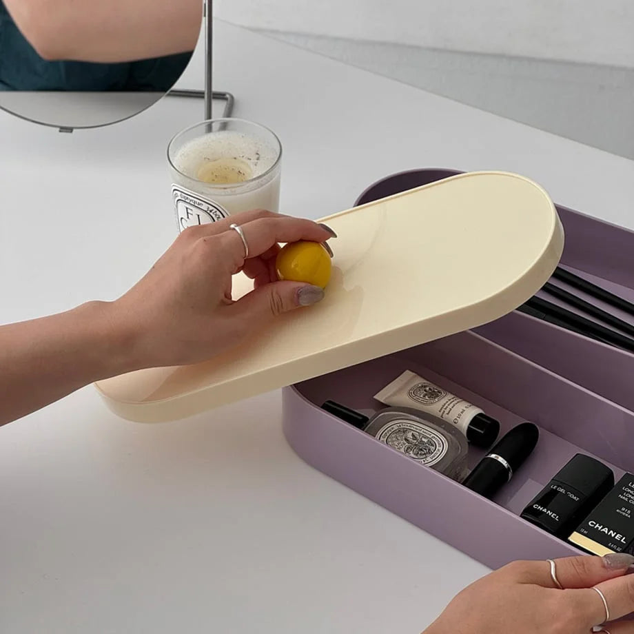 A person placing the cream lid onto the lavender makeup organizer on a desk.