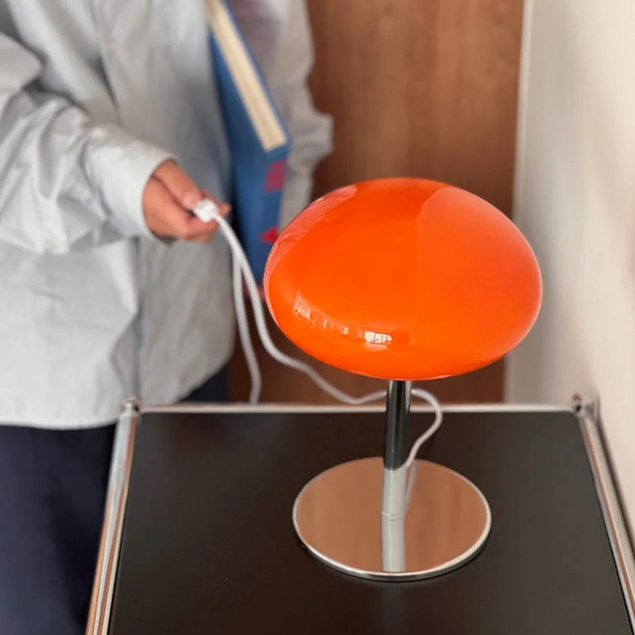 A person holding the white USB power cord for the orange mushroom lamp - RoomDen.