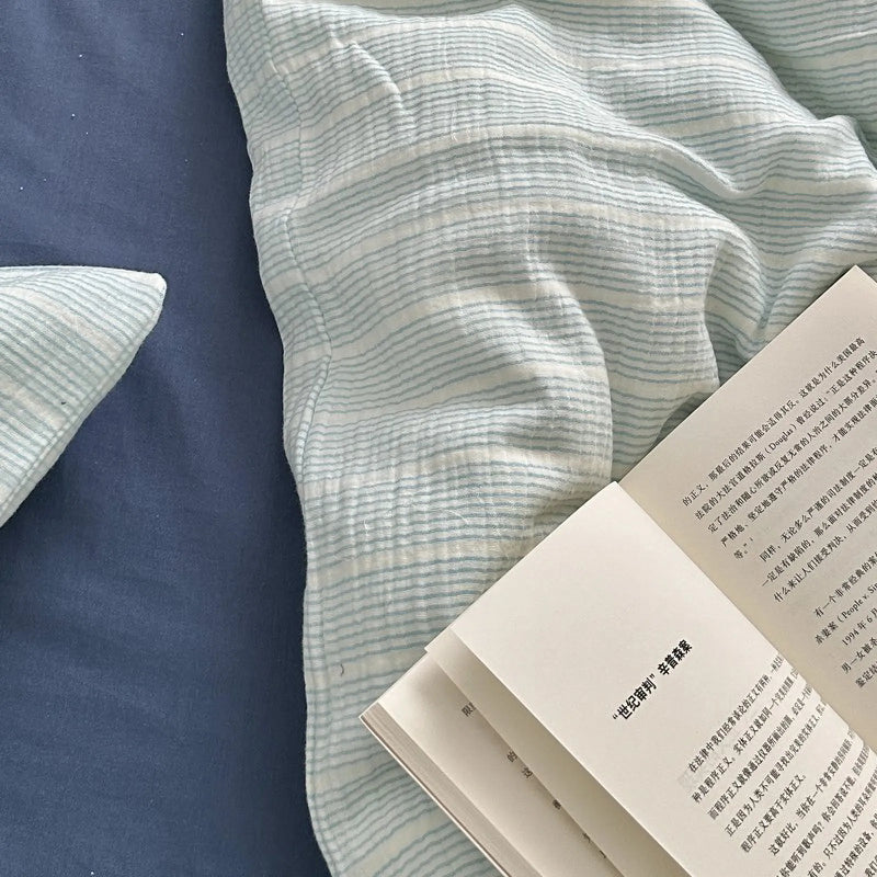 Close-up of the soft, crinkled folds of cyan pinstripe washed cotton, the drape that carries layer two.