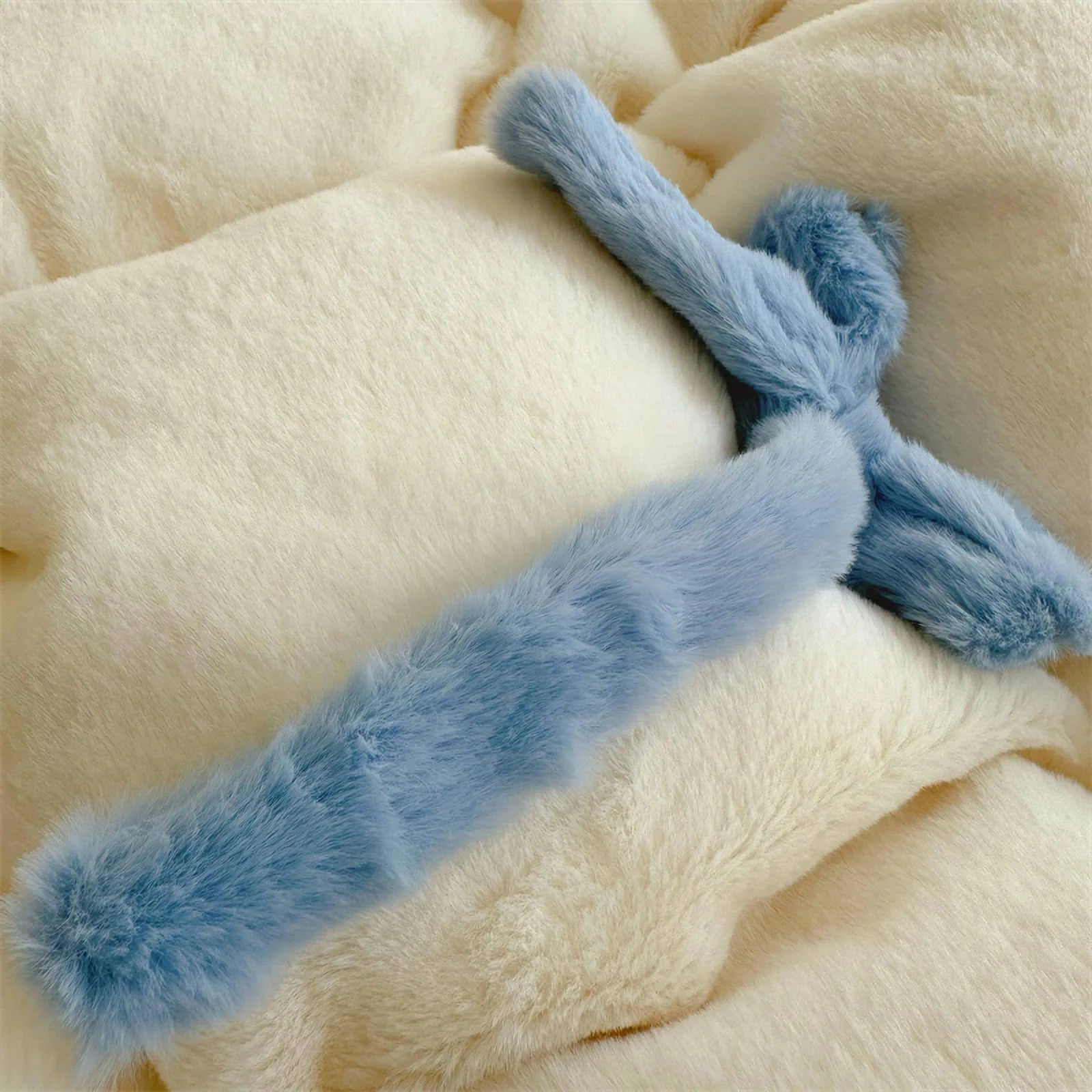 Macro shot of a blue plush bowknot on the creamy white fleece comforter.