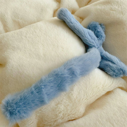 Macro shot of a blue plush bowknot on the creamy white fleece comforter.