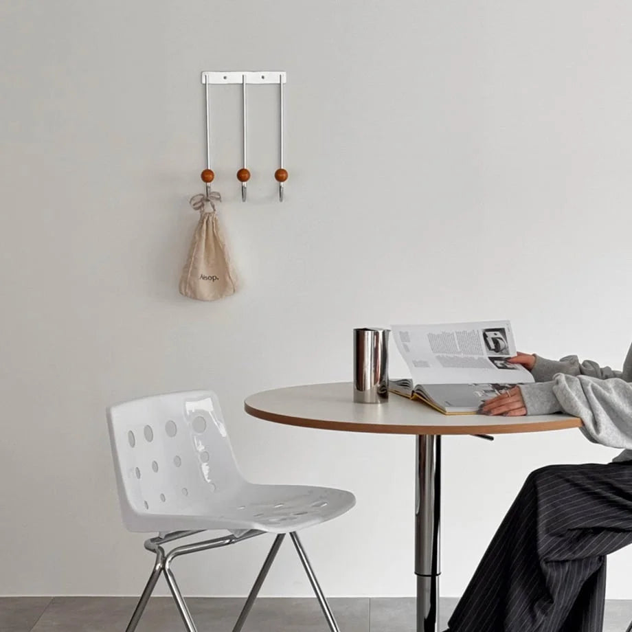 A wide shot of the Silver & Orange wall hooks in a minimalist dining or study area. - RoomDen