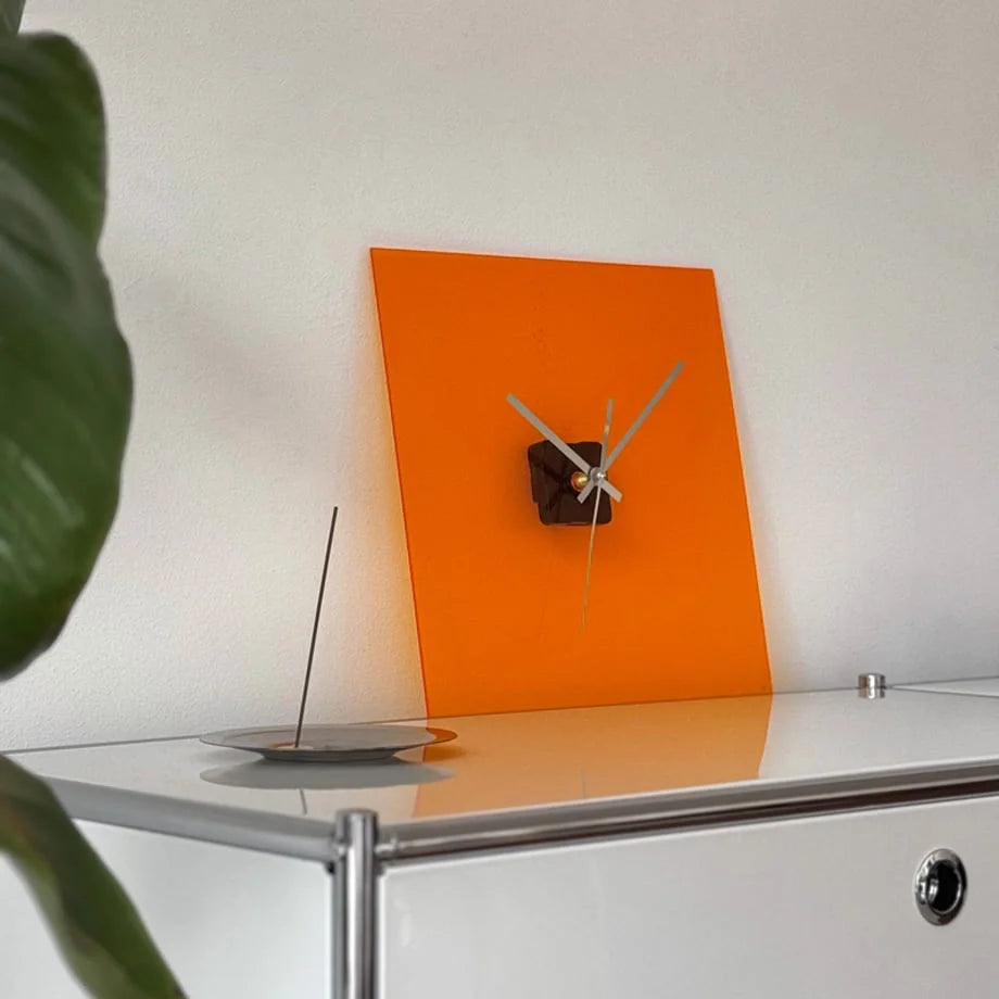 Close-up of the Vivid Orange acrylic clock on a white surface, showing its glossy finish. - RoomDen