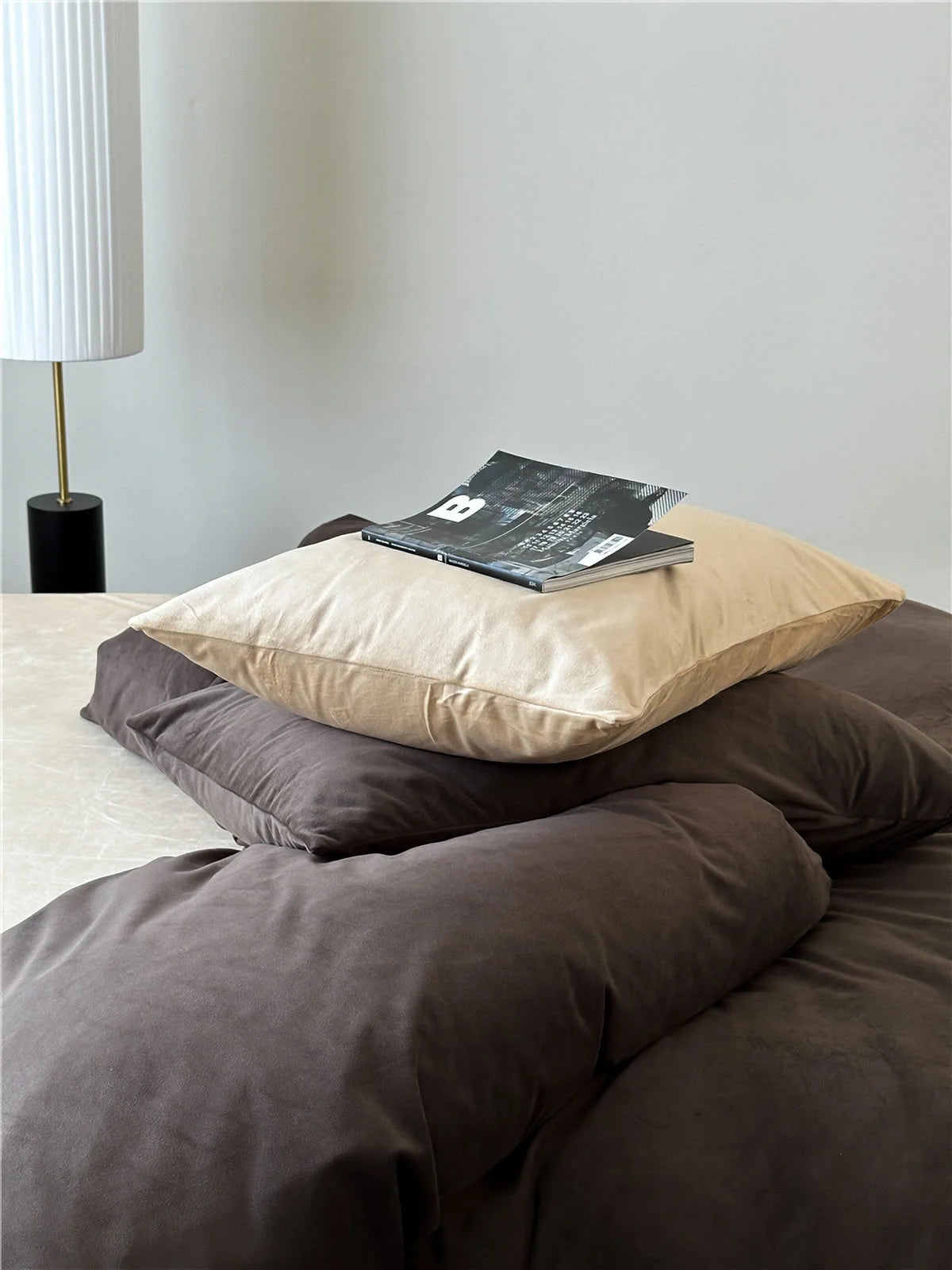 Close-up on the rich texture of the Mocha Brown and cream velvet pillowcases stacked on a bed. - RoomDen