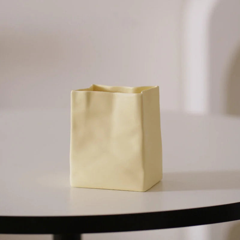 A single butter yellow crumpled ceramic organizer on a white table with soft lighting. - RoomDen