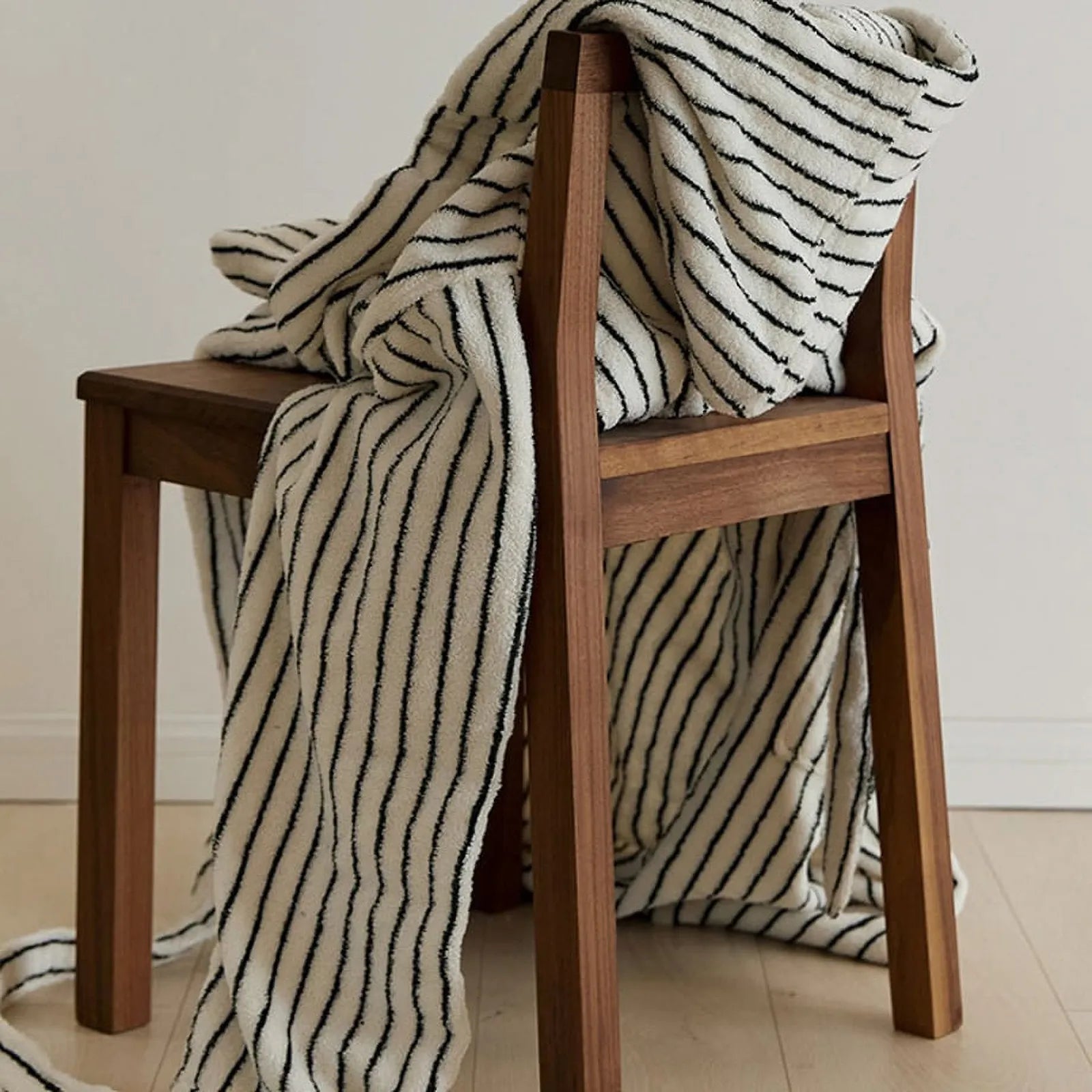 The cream striped robe draped casually over a wooden chair, showcasing the fabric's weight and drape.
