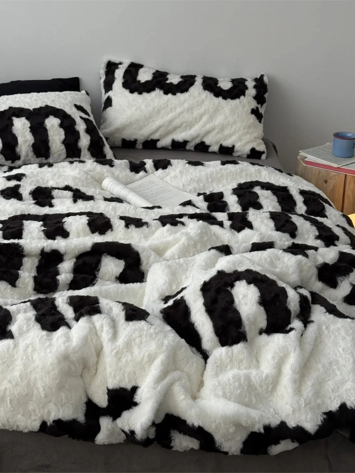 Plush black and white text print flannel fleece bedding set on a grey bed frame in a minimalist room. - RoomDen