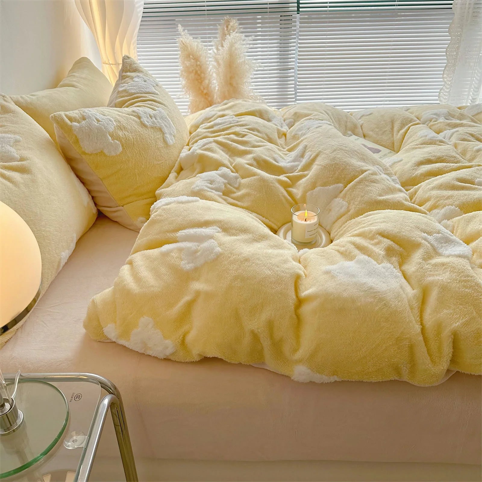 Close-up of a plush yellow flannel fleece bedding set with white teddy bear patterns, with a lit candle on the duvet. - RoomDen