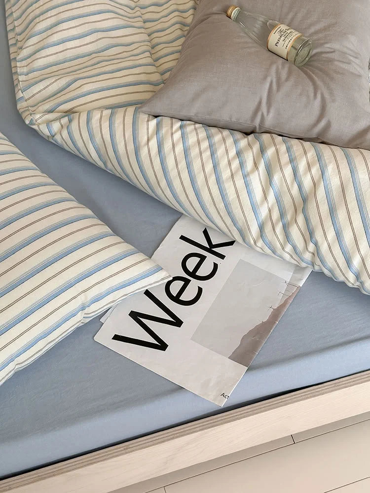 Close-up detail of the Blue Pinstripe Washed Cotton duvet cover and a grey pillow. - RoomDen