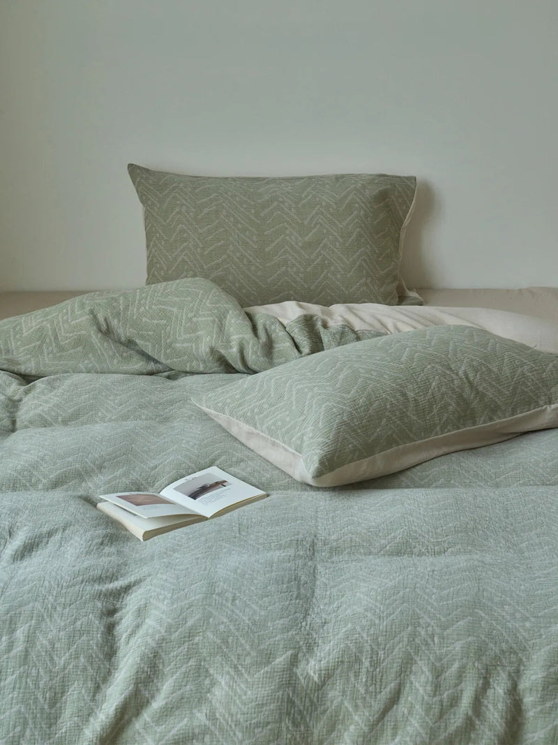 Soft Crinkled Geometric Washed Cotton Bedding Set styled on a bed with an open book, the texture reading settled and restful. — RoomDen