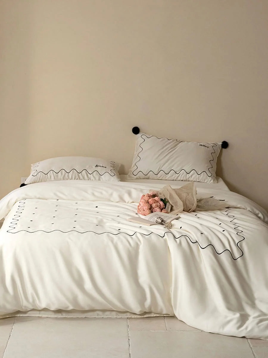 Full shot of a bed with the Creamy White & Black pom pom Tencel bedding set in a minimalist room. - RoomDen