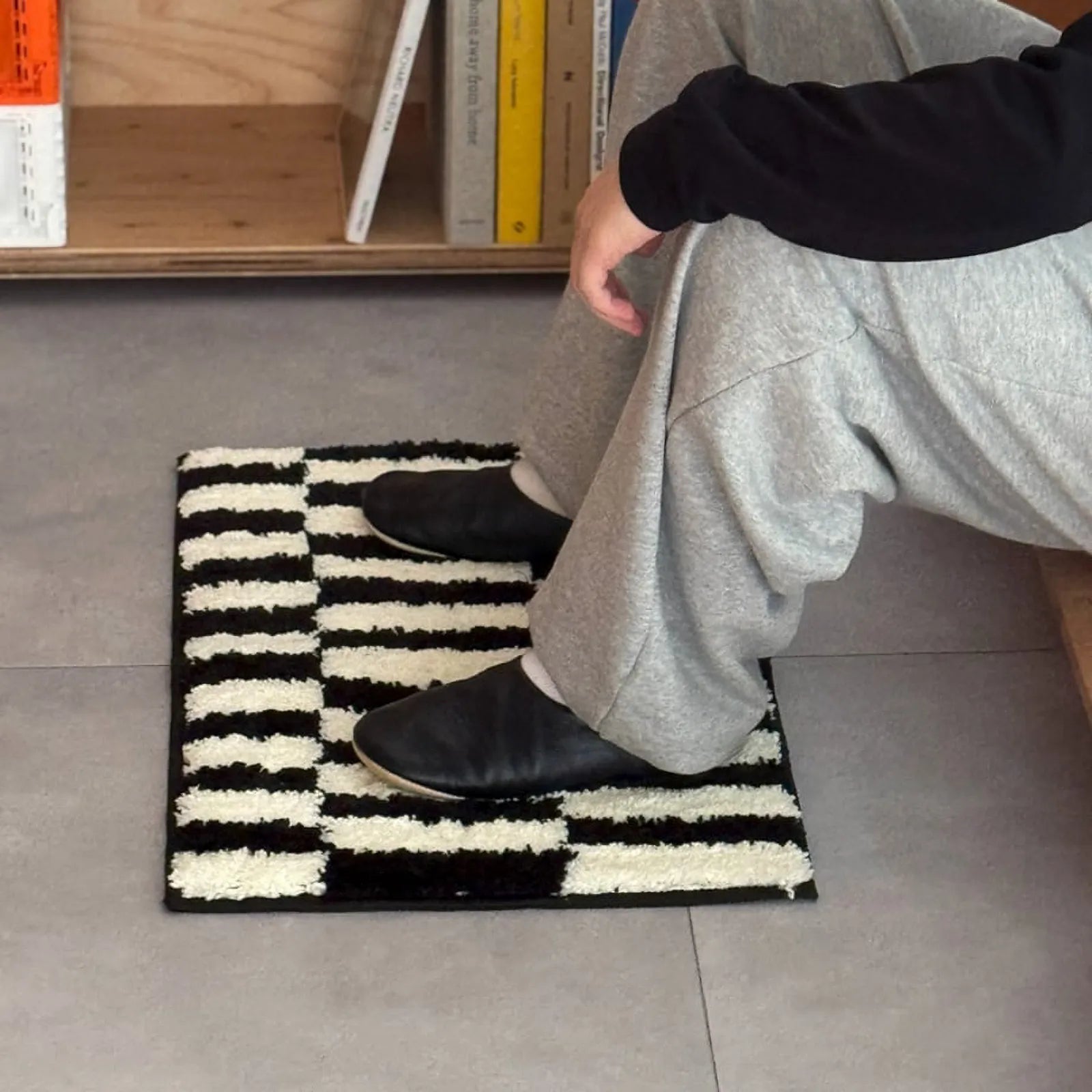 Lifestyle shot of feet resting on a soft black and white striped shaggy rug - RoomDen