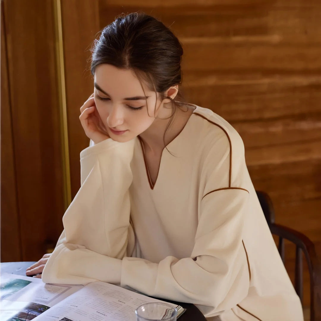 Model in the V-neck plush pajama top reading a magazine at a wooden table. - RoomDen