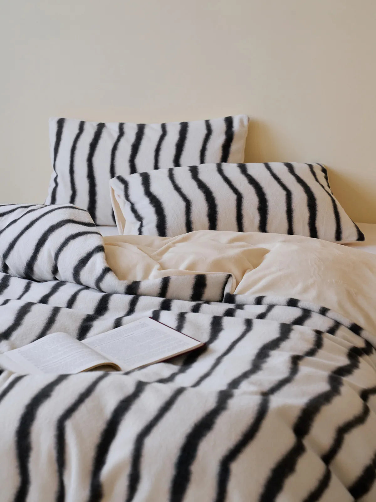 Fluffy black and white striped flannel fleece bedding set styled on a bed, showing the duvet and multiple pillows - RoomDen.