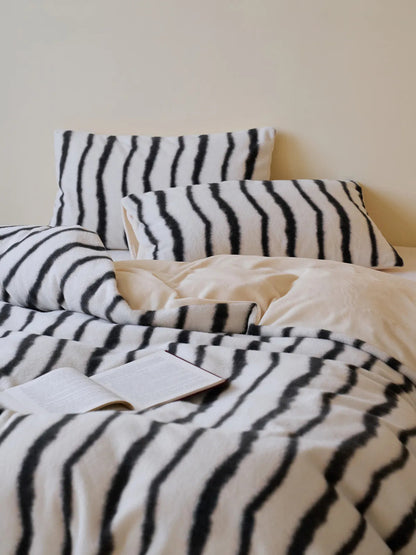 Fluffy black and white striped flannel fleece bedding set styled on a bed, showing the duvet and multiple pillows - RoomDen.