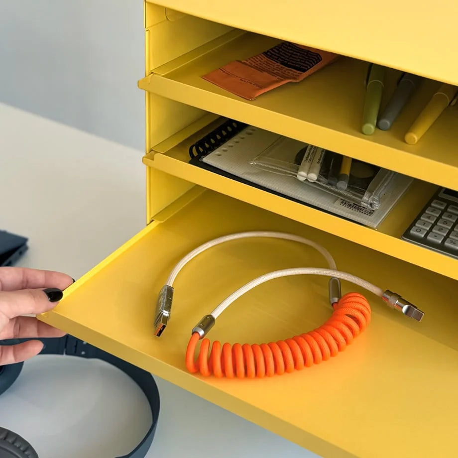Detail shot of a hand pulling out a tray from the Sunny Yellow metal organizer to reveal a cable - RoomDen.